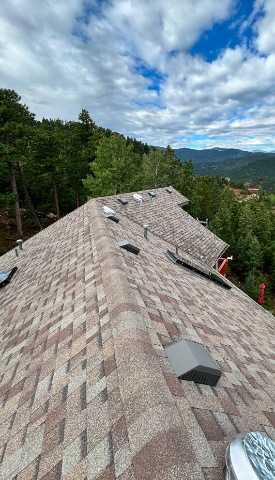 Steep asphalt shingle roof with a overlooking mountains and trees.