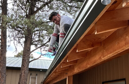 worker installing gutters on a roof of a Colorado home