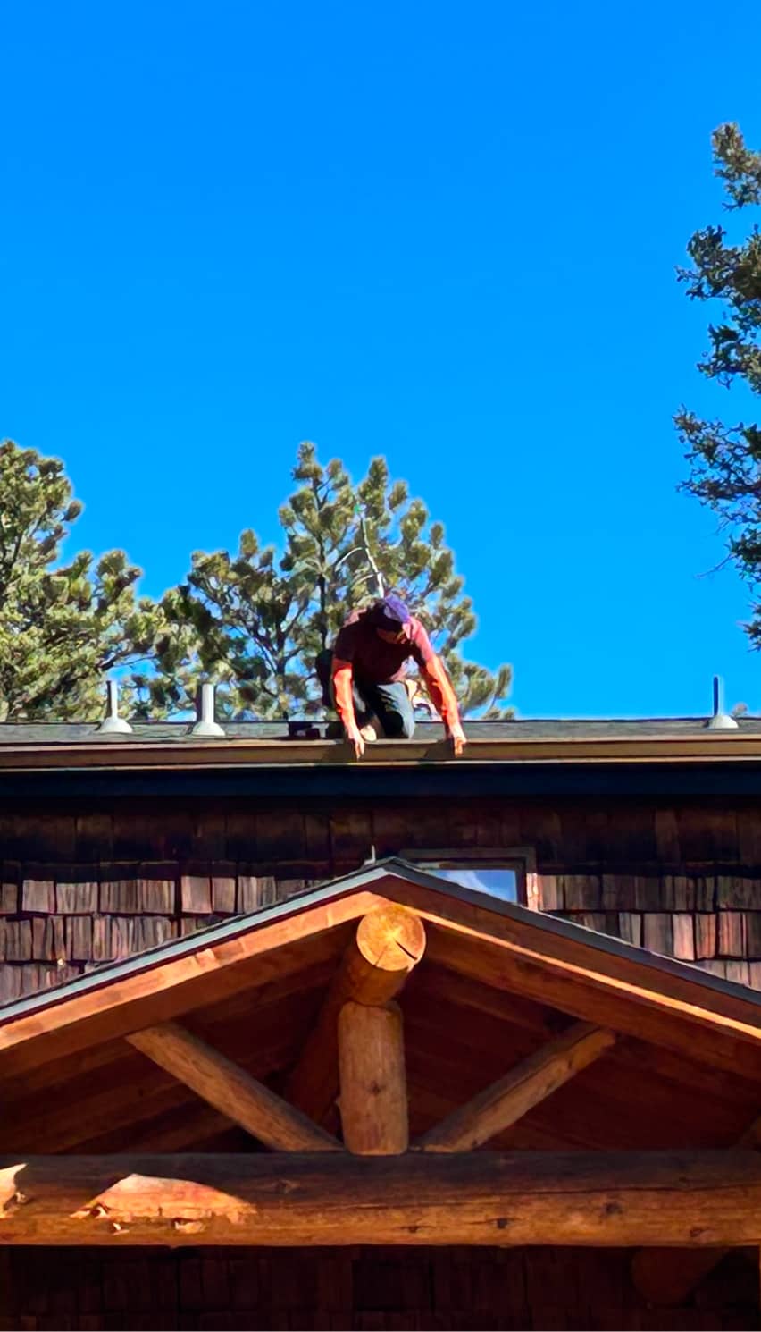 worker repairing a damaged roof by cutting and replacing bitumen shingles