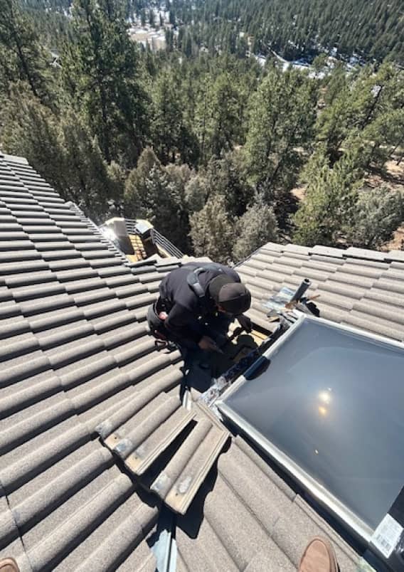 Worker inspecting roof area around skylight installation